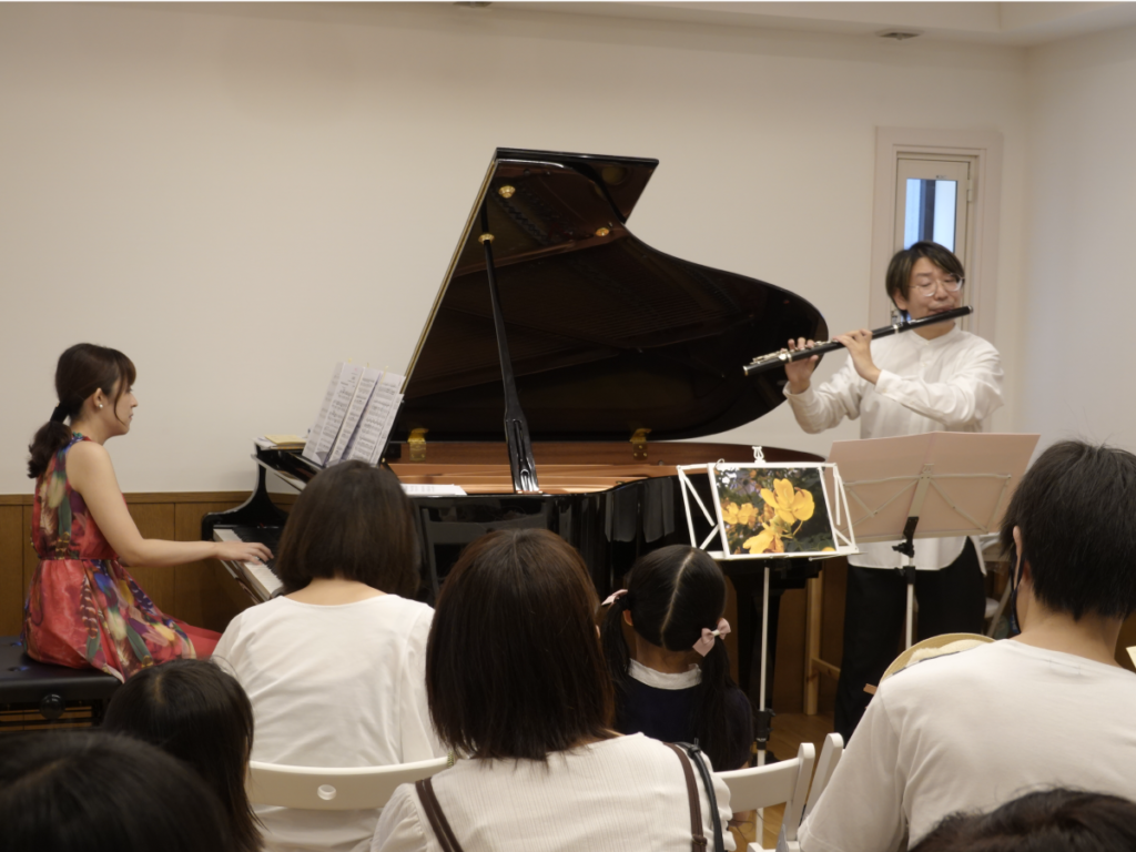 客席の親子の前で、フルートとピアノを演奏している様子